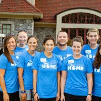 Alumni pose in front of the Alumni House